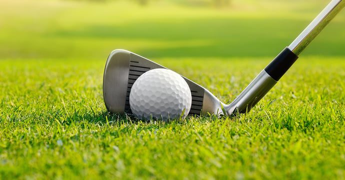 Closeup of an iron golf club lined up against a golf ball