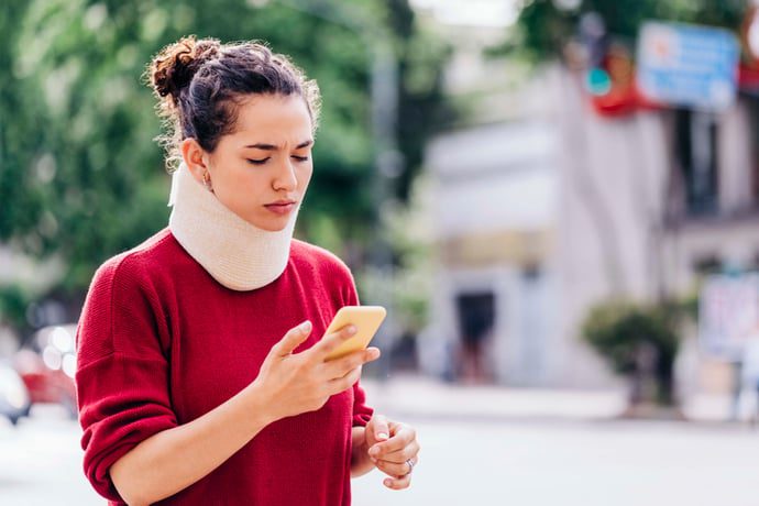 A woman with a neck injury calling her insurance after a car accident