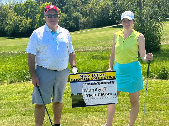 Attorneys hold sponsorship sign at the Mike Dillett Memorial